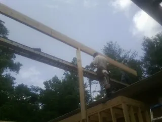 Carpenter setting a ridge beam over a new addition frame — Ice Dam Removal by Roofing Brothers in Whitesburg