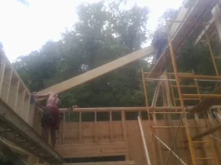 Carpenter raising a rafter beam on a new second story frame in Whitesburg
