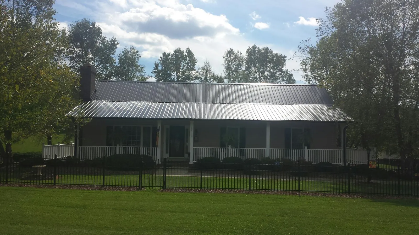 Gray metal roof on a brick ranch with a full width front porch — Gutter Guard Installation work by our crew in Whitesburg